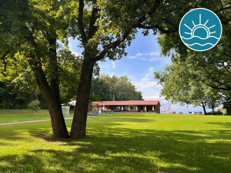Grüne Wiese mit Bäumen vor dem Kiosk am Krummweiher.